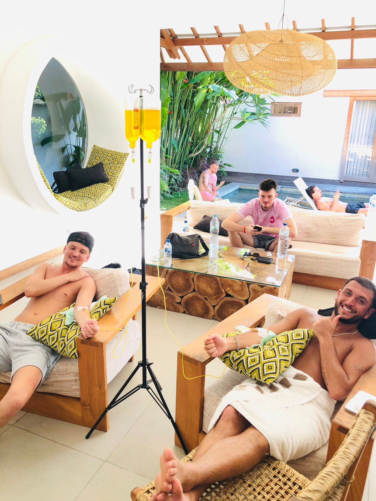 Two men receiving a mobile IV drip therapy while relaxing in a luxury Bali villa.